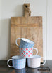 wooden cutting board with floral enamel mugs